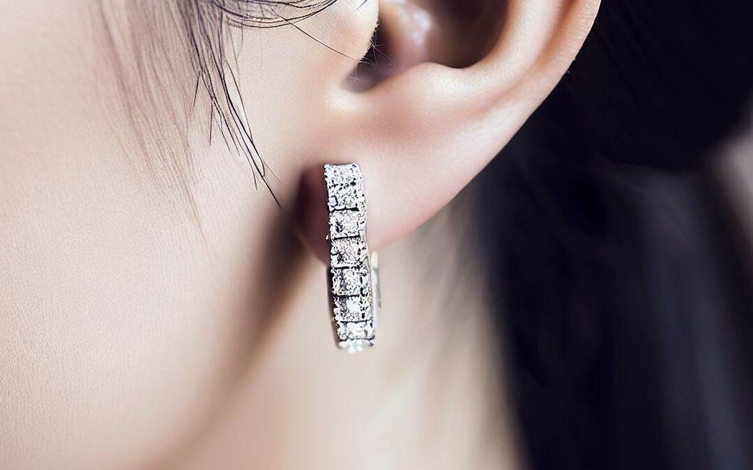 A woman wearing diamond huggie earrings.