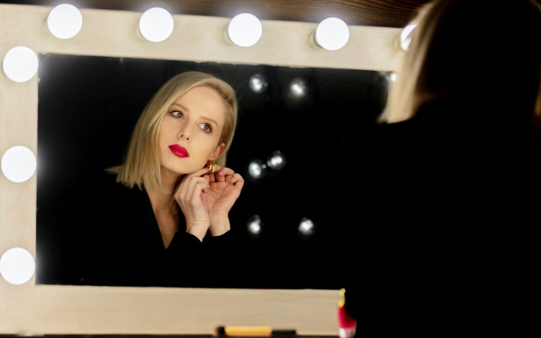 Beautiful blonde woman wearing diamond stud earrings near makeup mirror