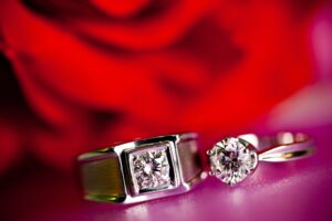Couple Diamond Rings Closeup With A Blurred Red Background. The Wedding Ring.