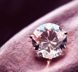 A Close-Up Of A Shimmering, Light Pink Lab-Grown Diamond, Placed On An Elegant Velvet Backdrop.