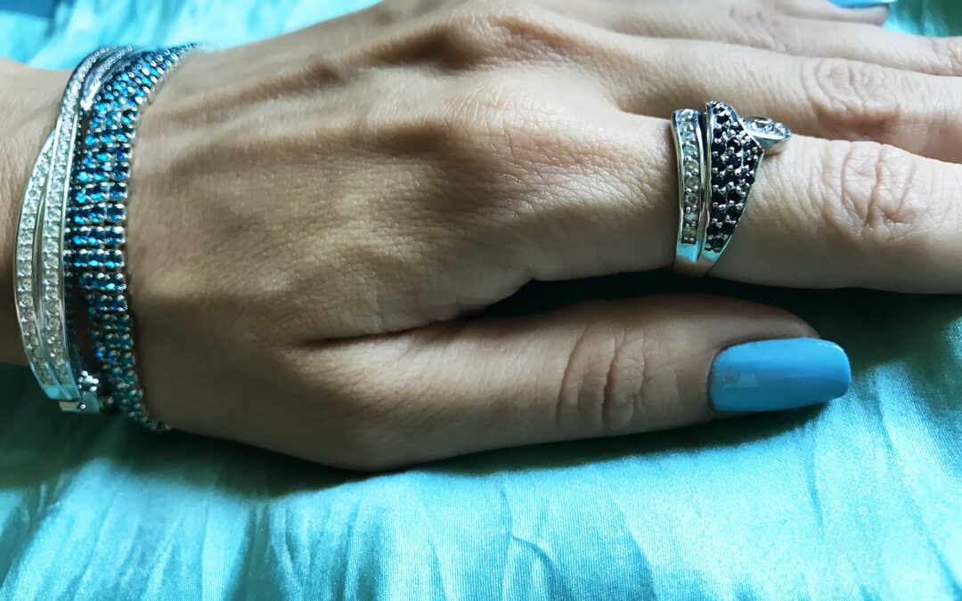 Discover diamond bracelets - Hamd of a Young Woman with Blue Manicure and Fashionable Blue Bracelet and Ring on Blue Background