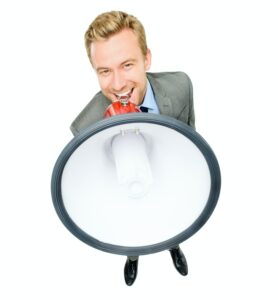 High Angle Shot Of A Handsome Young Businessman Standing Alone In The Studio And Using A Megaphone