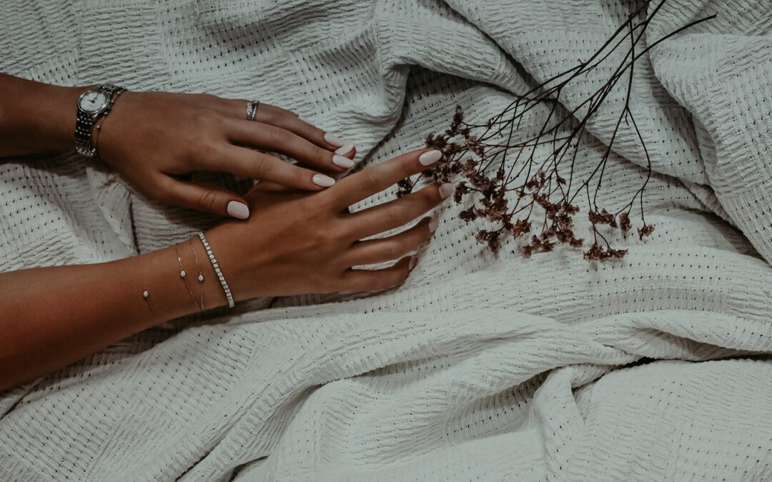 hands with white nail polish touching dried flowers